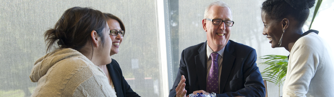 Business students and Concordia University sit around a table and talk with their professor