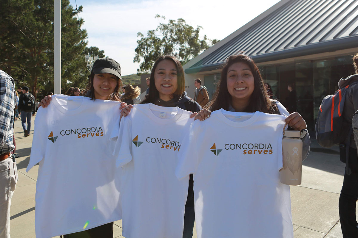 Three students showing their Concordia serves shirts