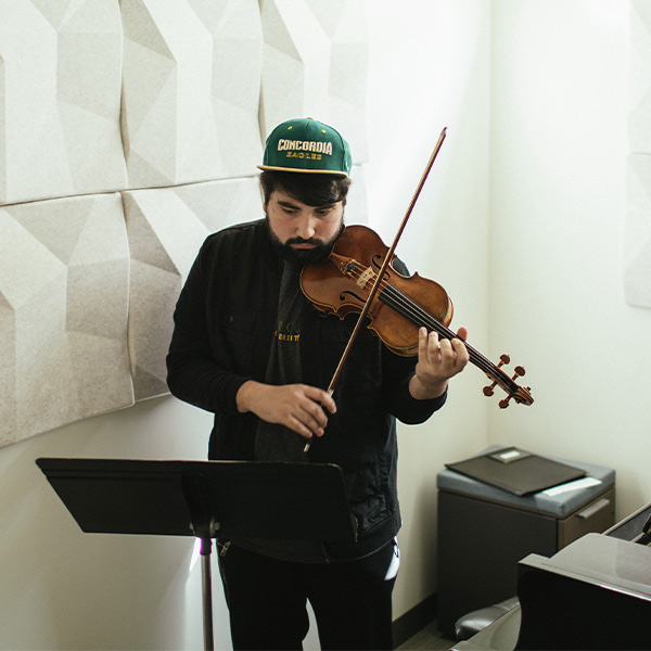 Aris practicing the violin inside a practice room