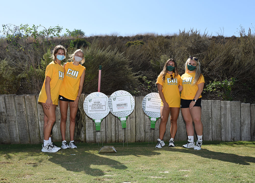 CUI students standing in front of Eagle Golf Classic signs