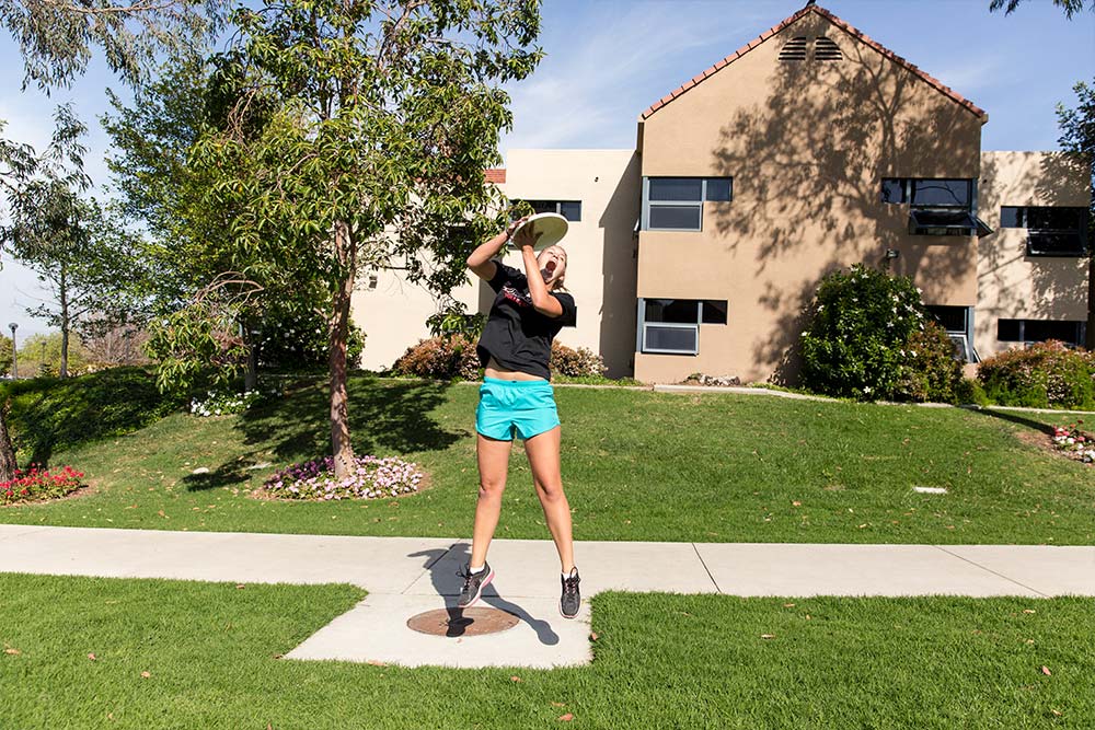 A student makes a catch in a game of ultimate frisbee.