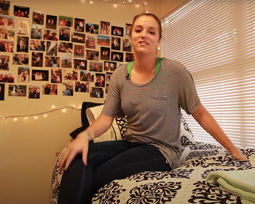 Student sitting on her dorm bed