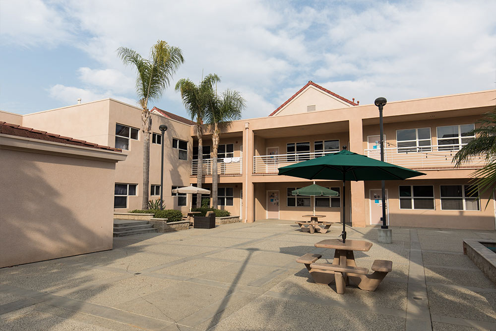 A courtyard of the Residence Halls with outdoor tables shaded by umbrellas