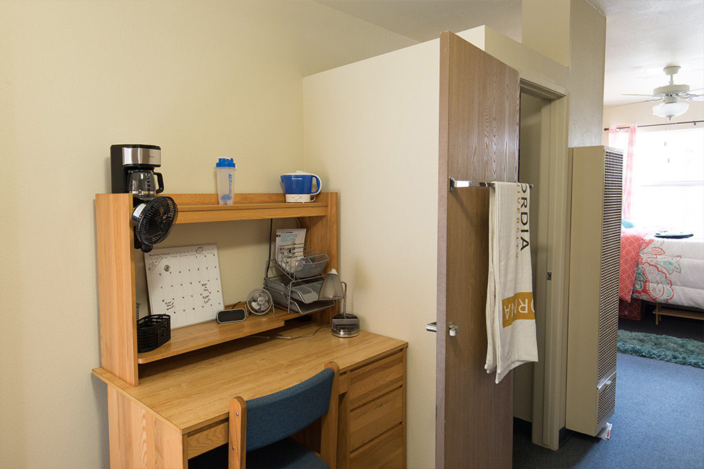 A desk, desk topper, and closet in a dorm room in Chi Rho