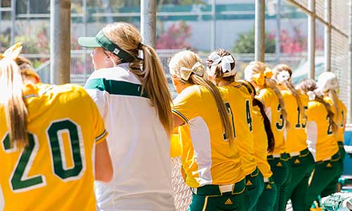 softball players waiting in the dugout