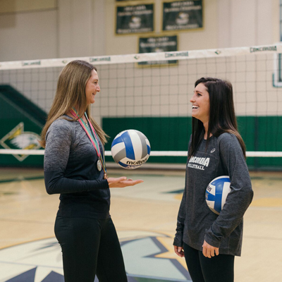 two student athletes talking on the volleyball court