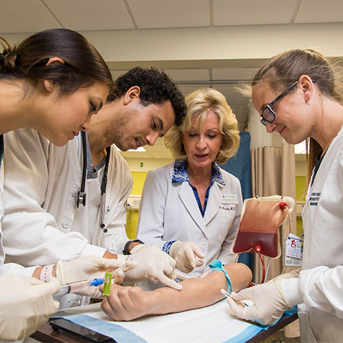 Nursing students learning how to inject blood into a practice arm