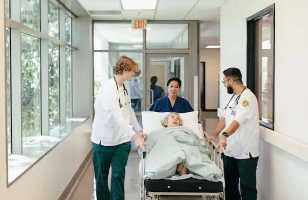 Nursing students moving patient in hospital bed down the hall