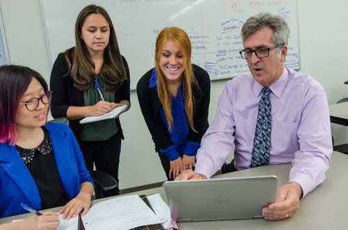 Students and mentor working around a computer