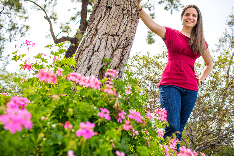 Deusch standing next to flowers and tree