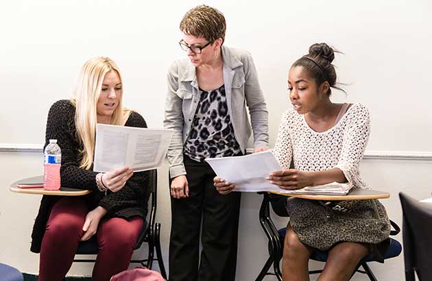 two students reviewing an assignment with a professor