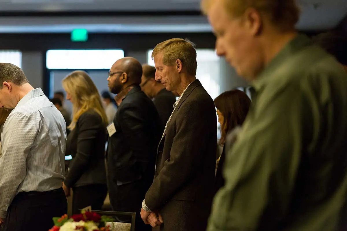 Attendees bowing their heads for prayer