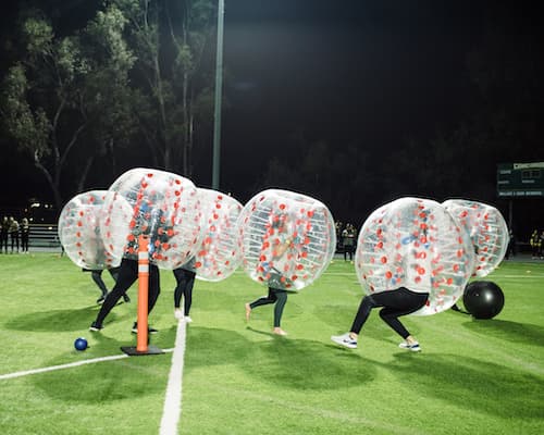 People playing soccer in inflatable bubbles