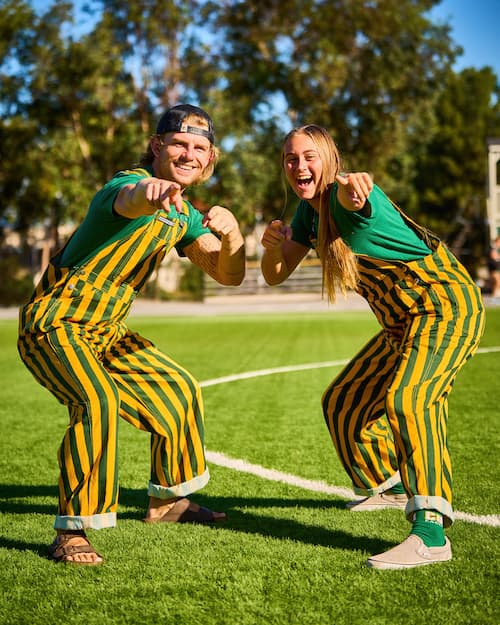 Two people smiling and pointing at the camera