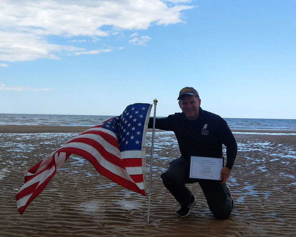 Dr. Held holds certificate presented by mayor of Colleville-sur-Mer for D-Day performance