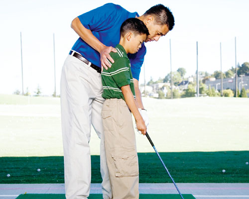 Father teaching his son how to golf.
