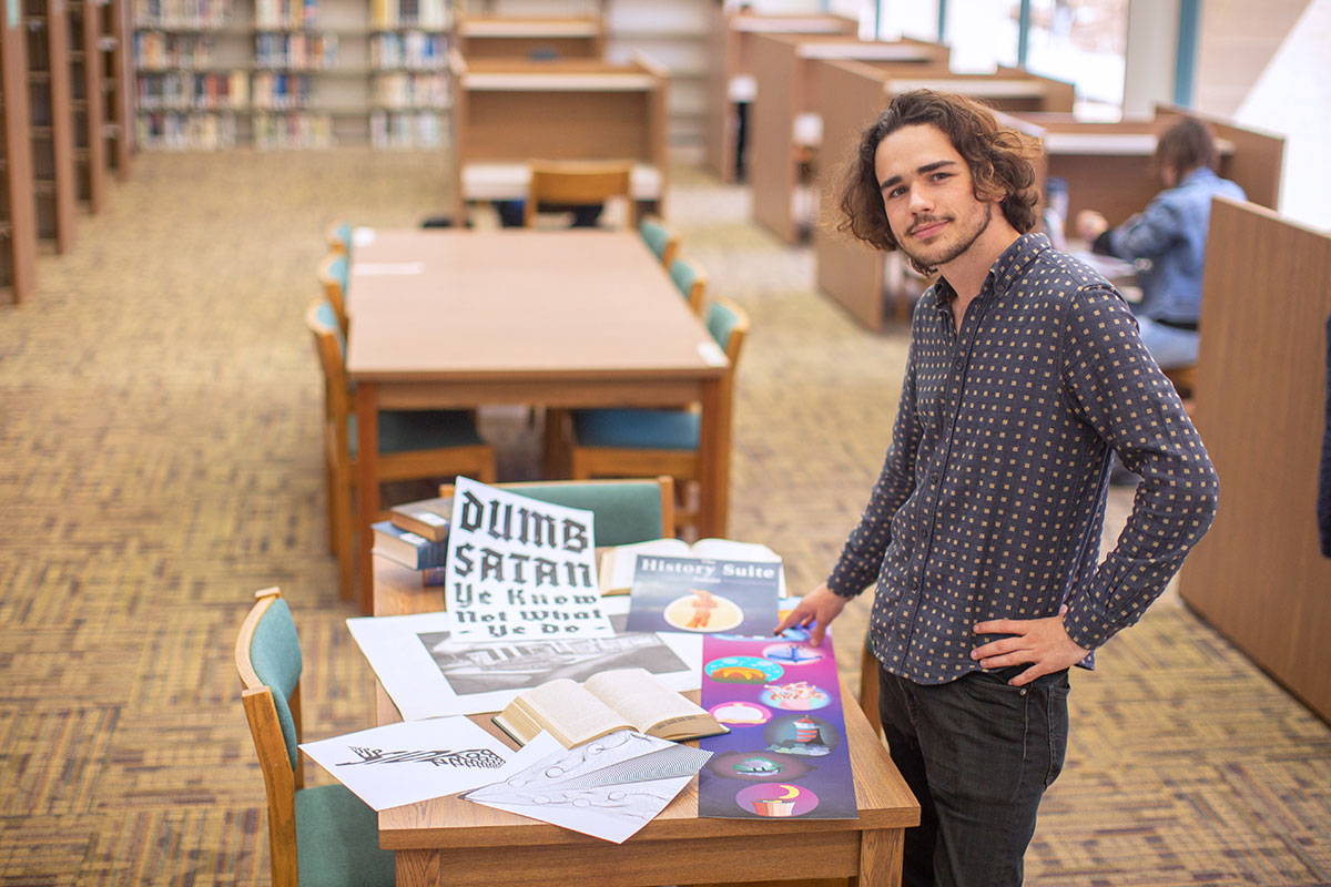 Augustine Mallinson standing next to a table with a variety of projects displayed