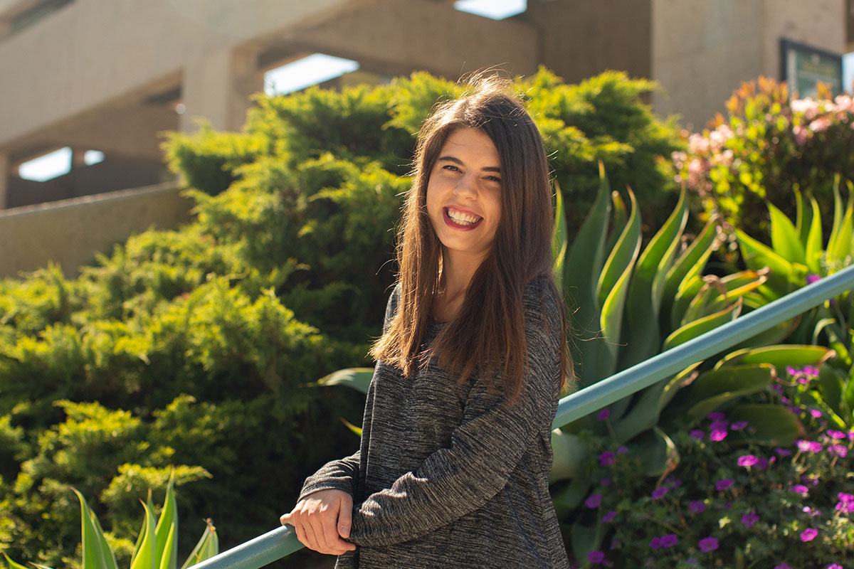 Emily McCarthy standing in front of foliage