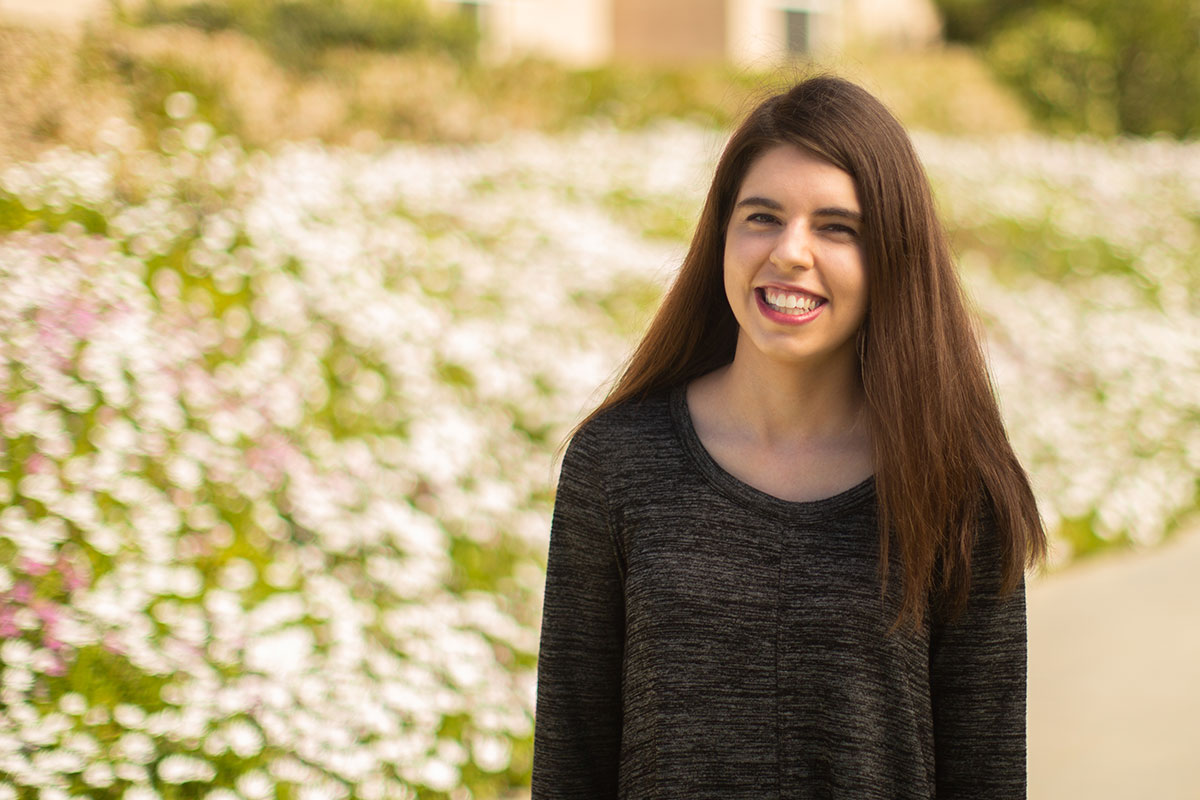 Emily McCarthy standing in front of bed of flowers