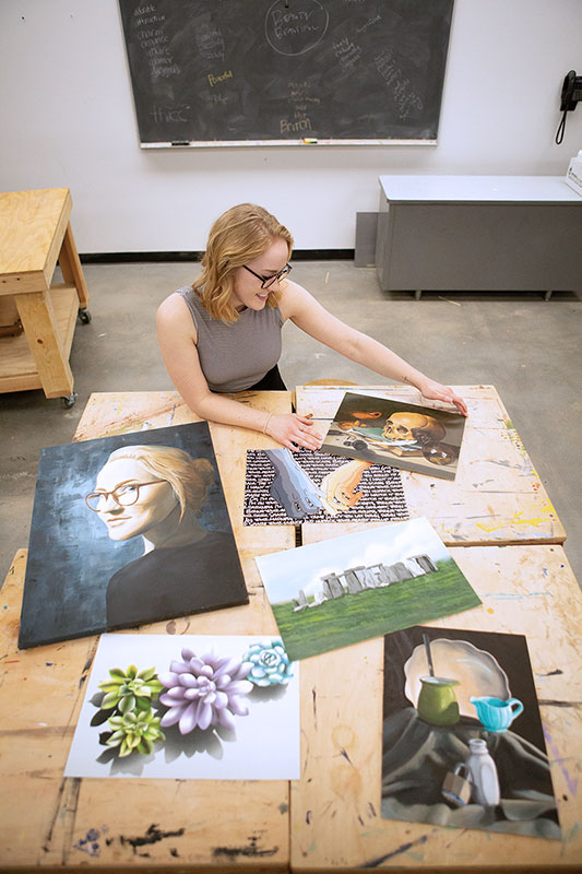 Sami Newport looking at a table covered with an assortment of her projects