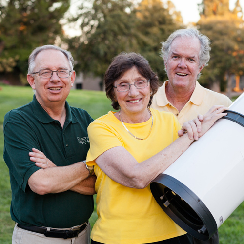 Faculty members pose in front of a telescope