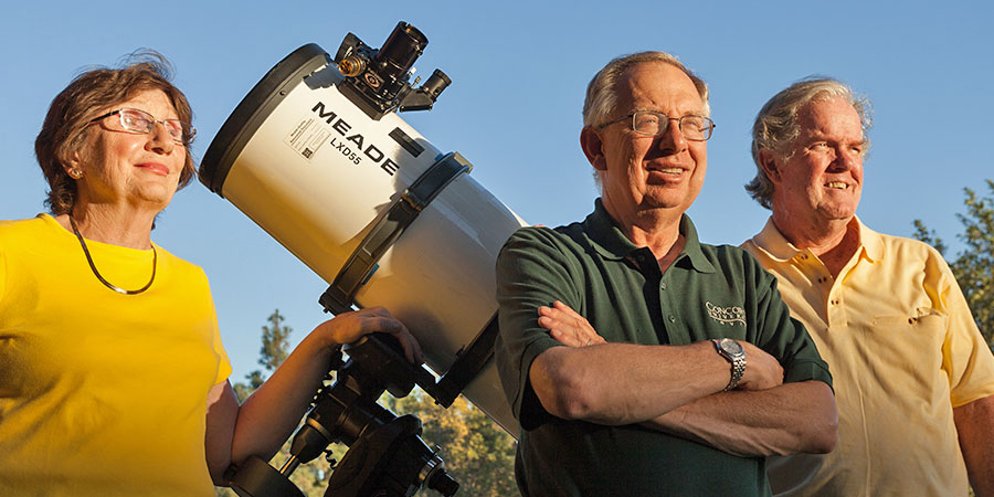 Faculty members pose in front of a telescope
