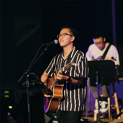 Brandon Li leads the crowd in worship while playing his guitar.