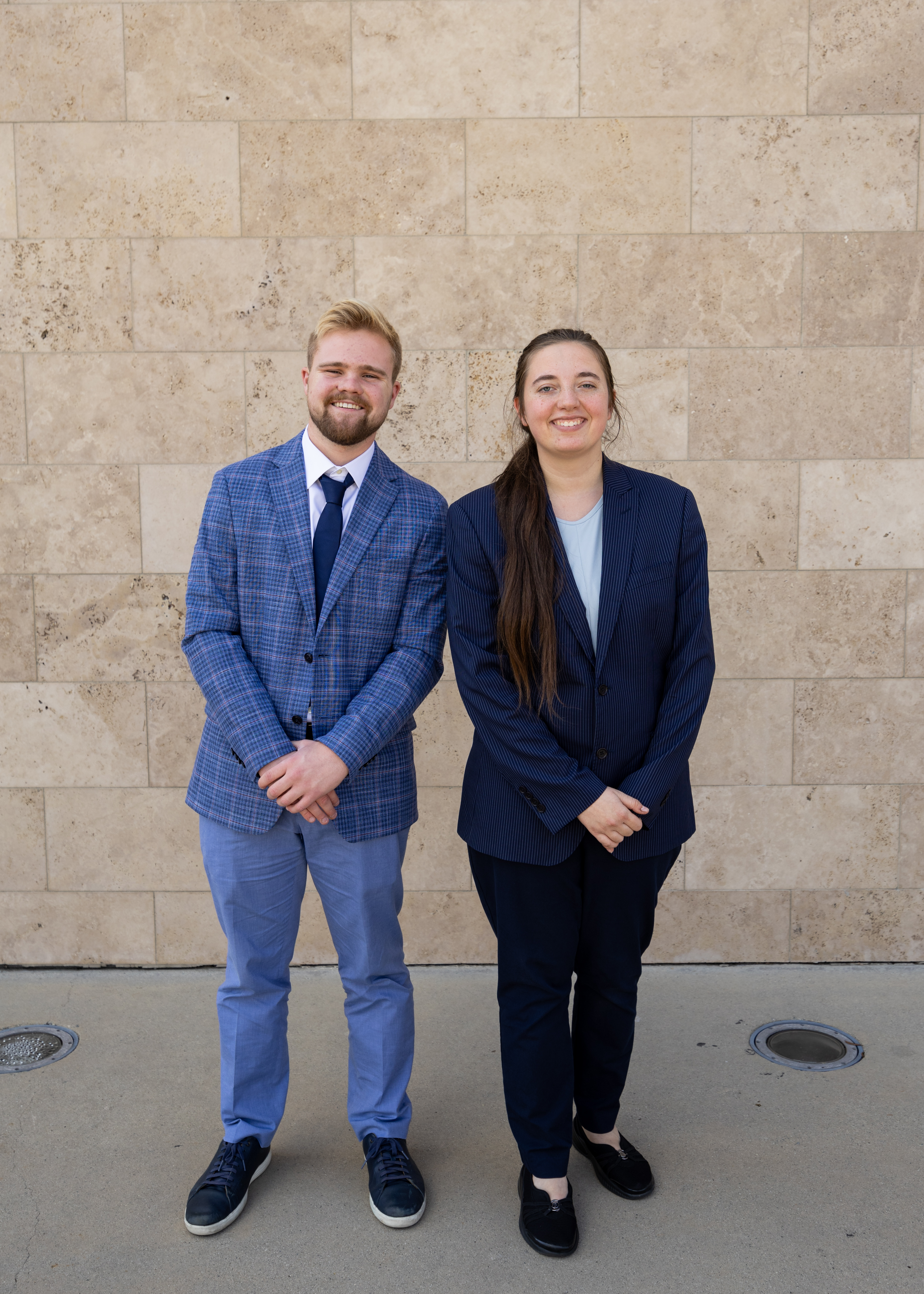 A man and woman standing in front of a stone wall