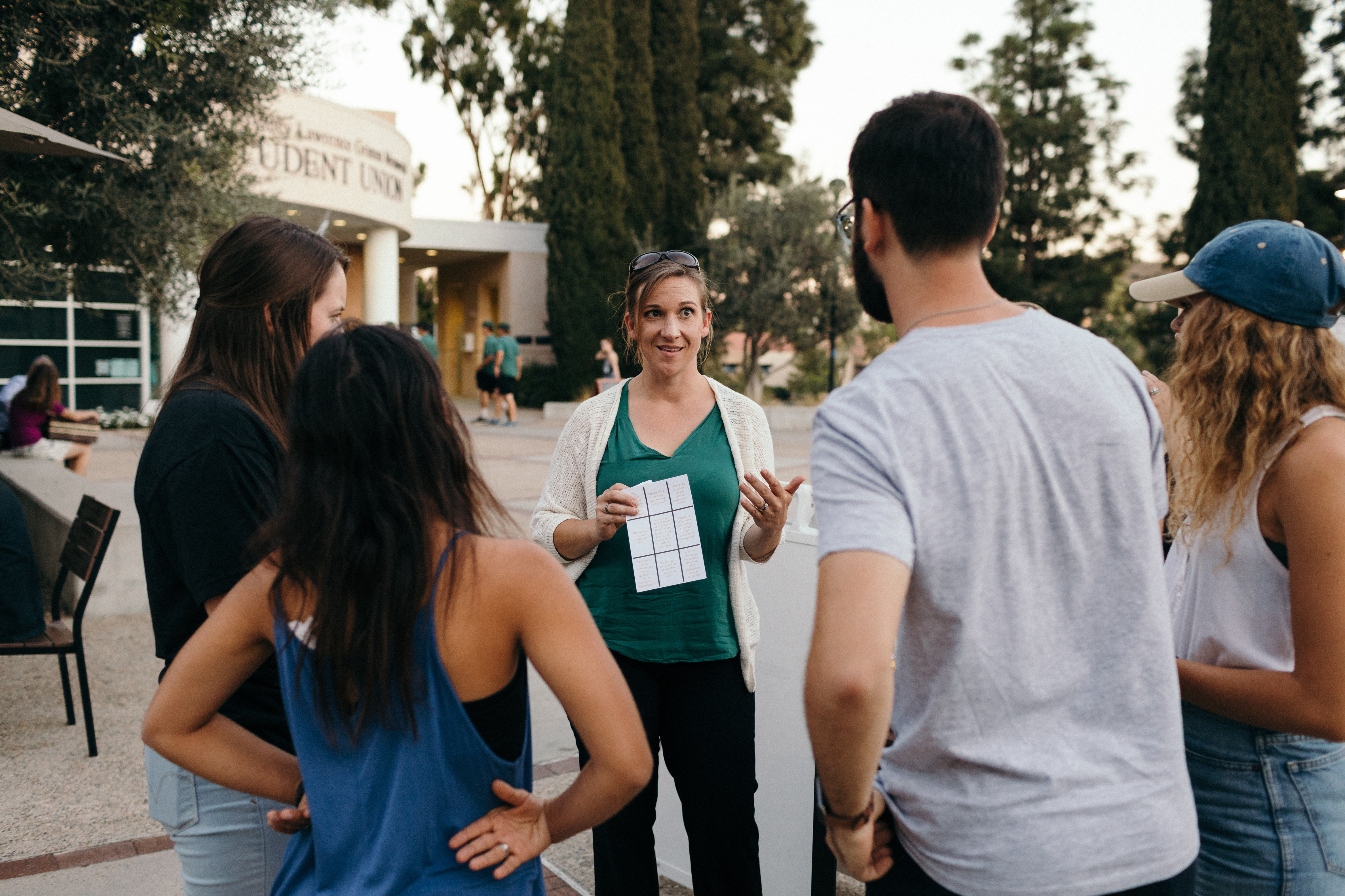 A woman holding a piece of paper with a group of people around
