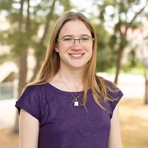 A woman wearing glasses and a purple shirt