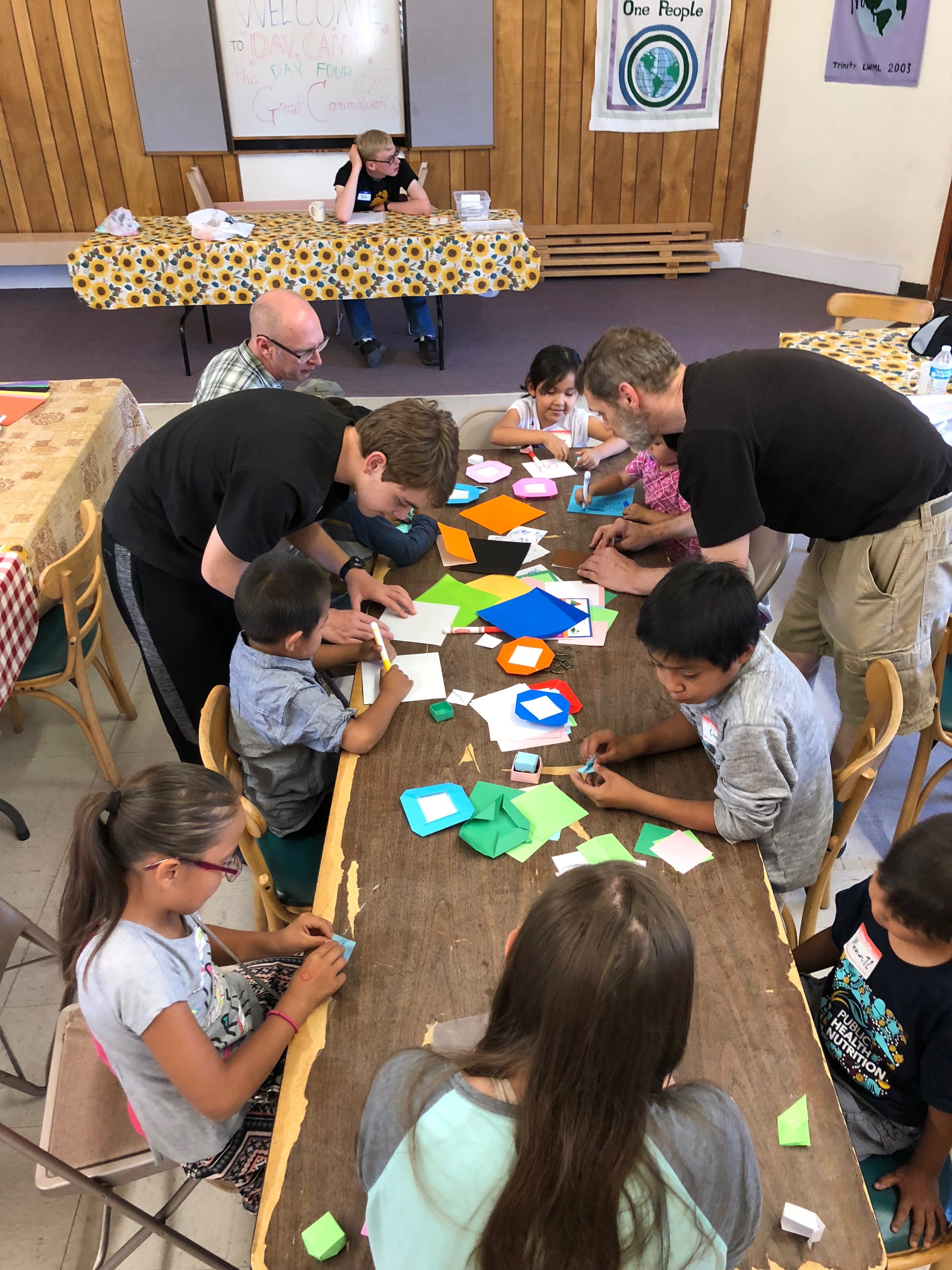 A group of people sitting around a table with paper squares