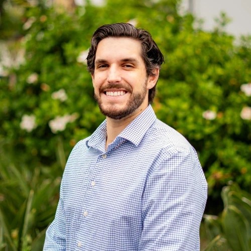 A man smiling in front of bushes