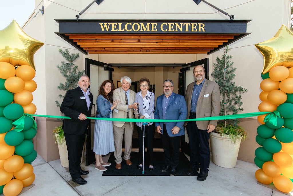 A group of people standing in front of a green ribbon