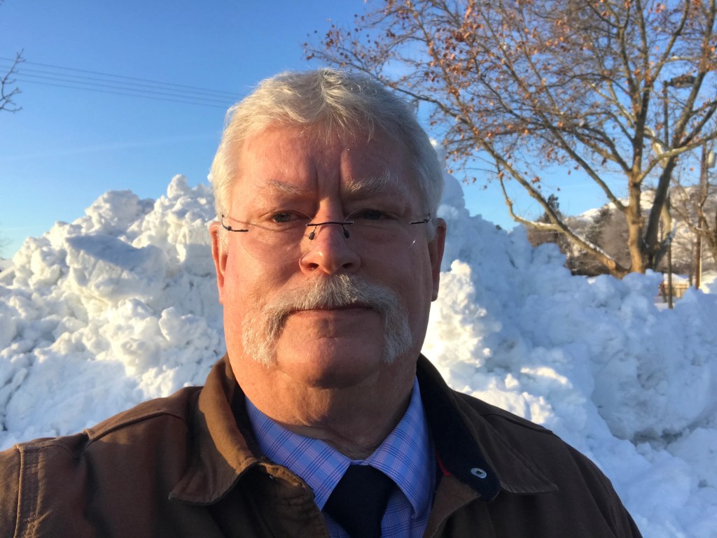 A man with a mustache and glasses in the snow