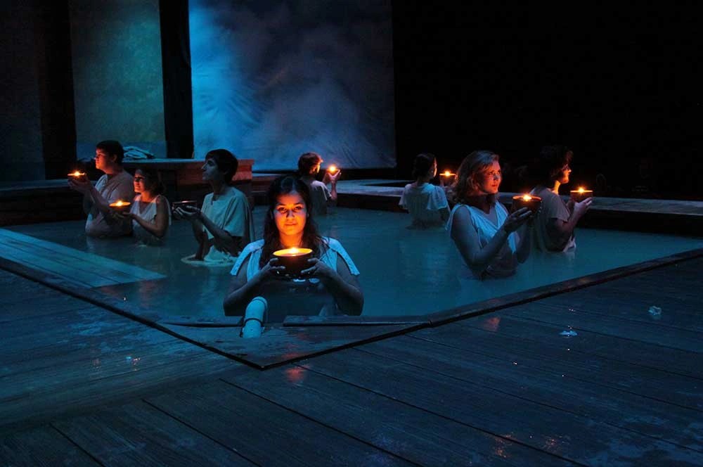 A group of women holding candles in a pool