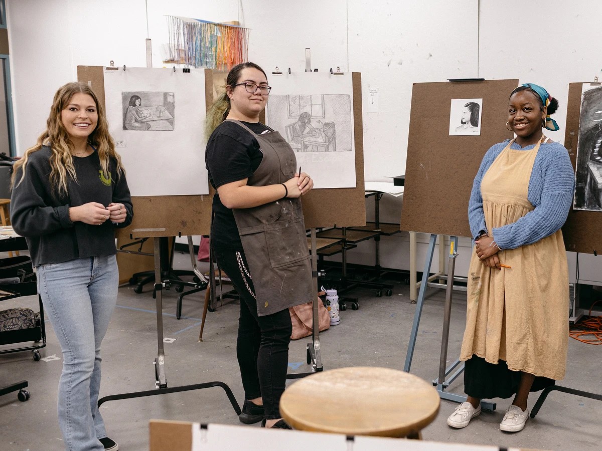 A group of women standing in a room with easels