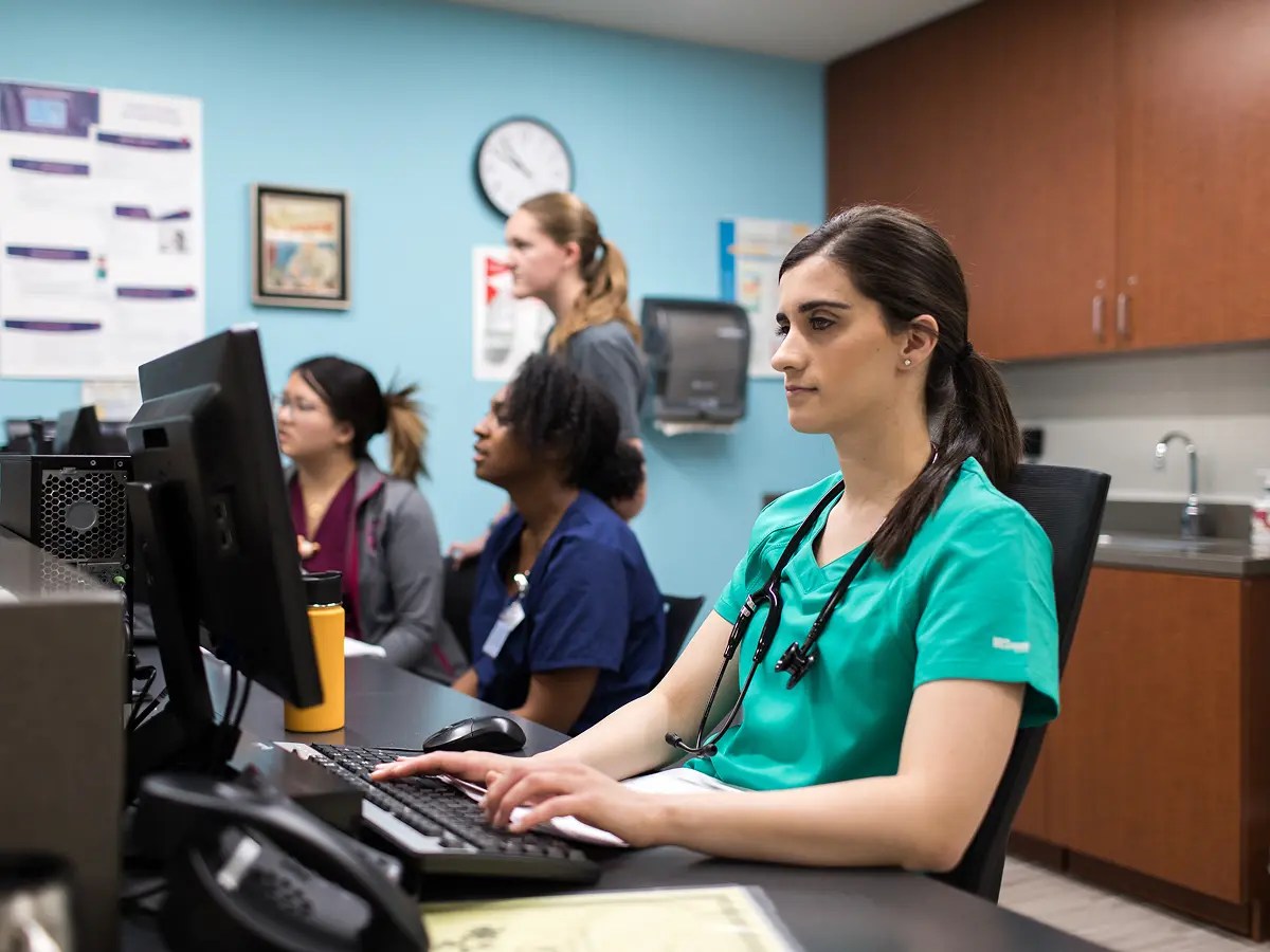 A woman in a scrubs using a computer