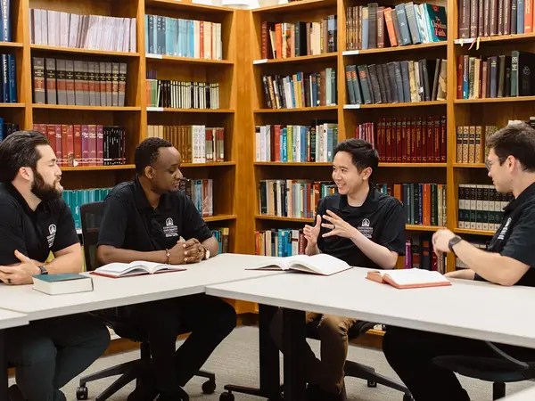 A group of people sitting at a table with books