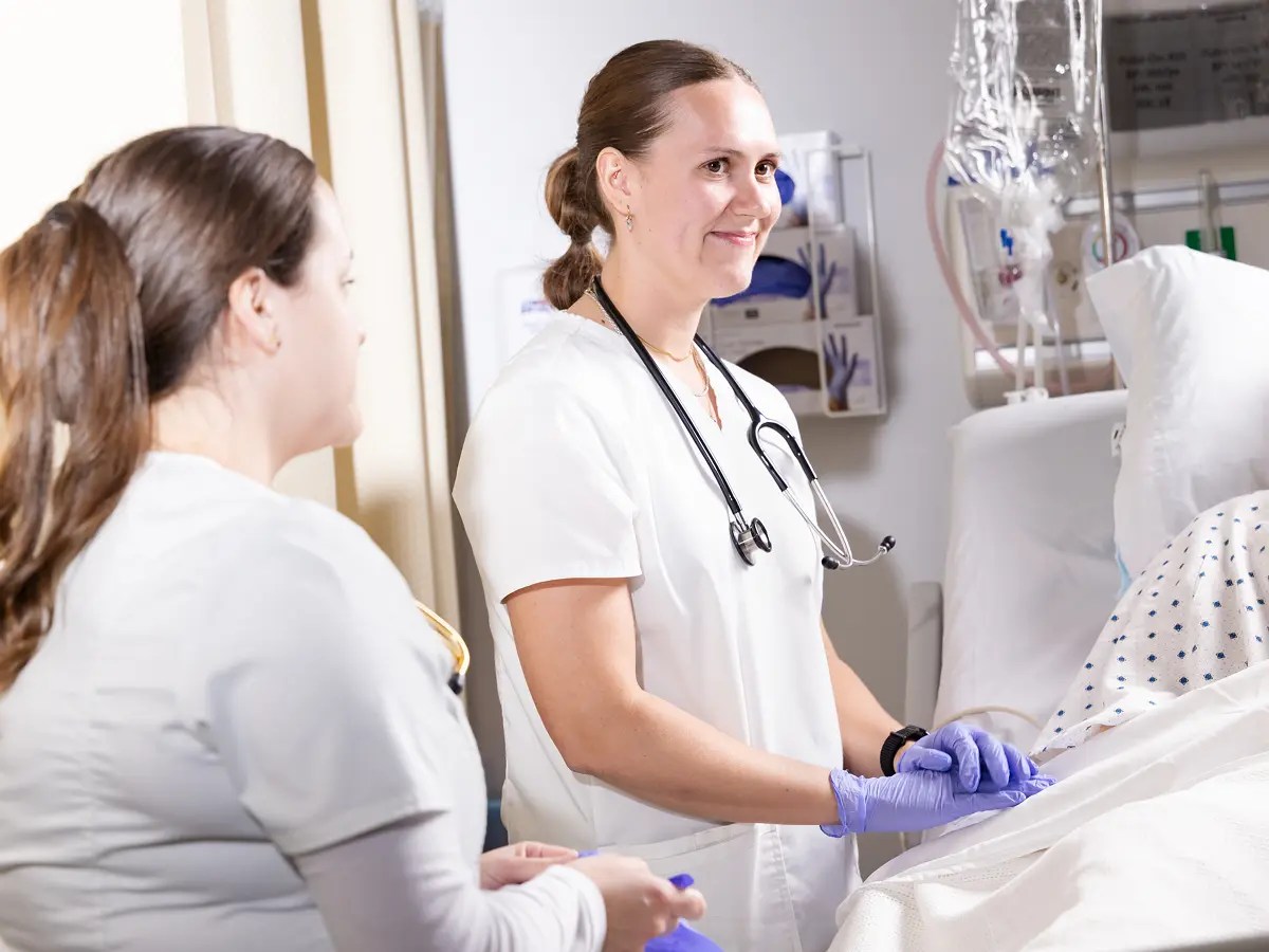 A woman in a white coat and stethoscope holding a patient