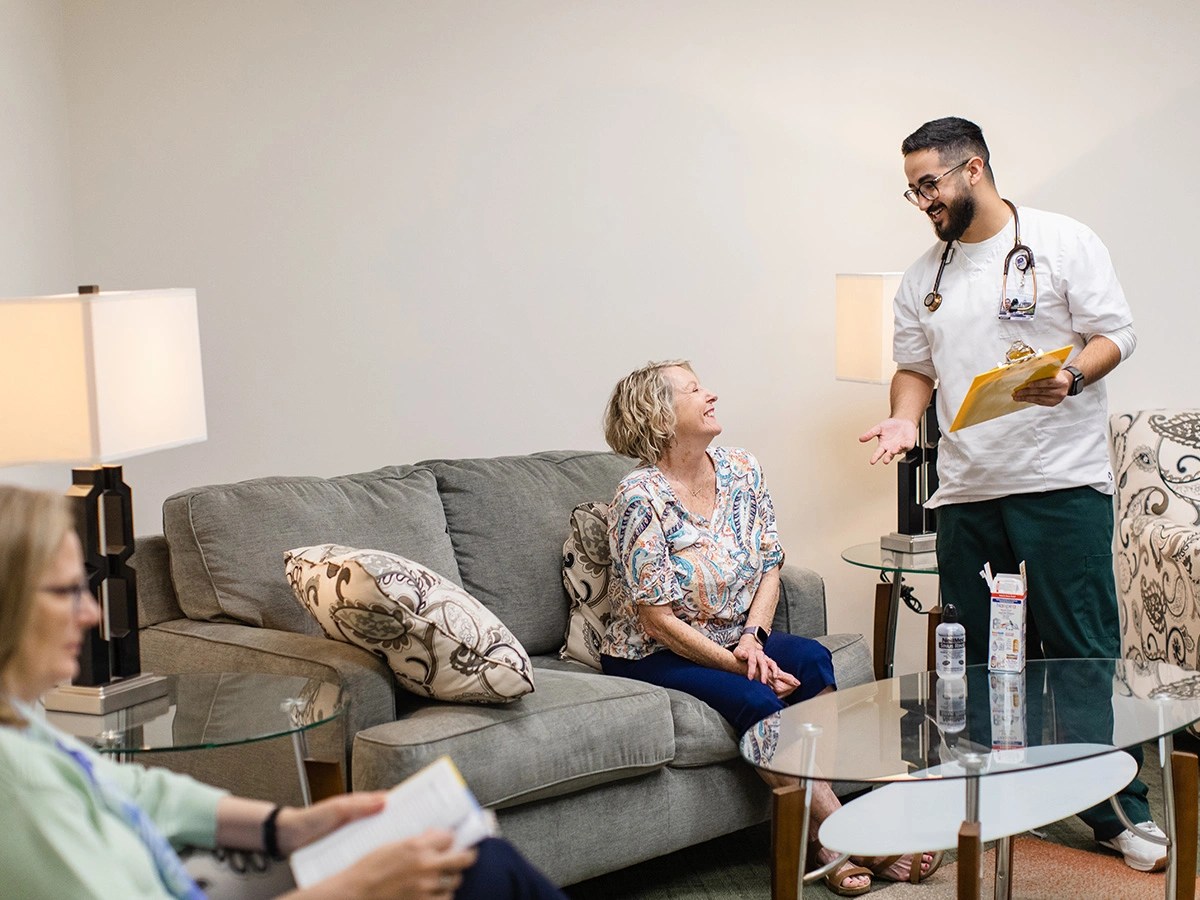 A man in a white shirt and a white shirt standing next to a woman sitting on a couch