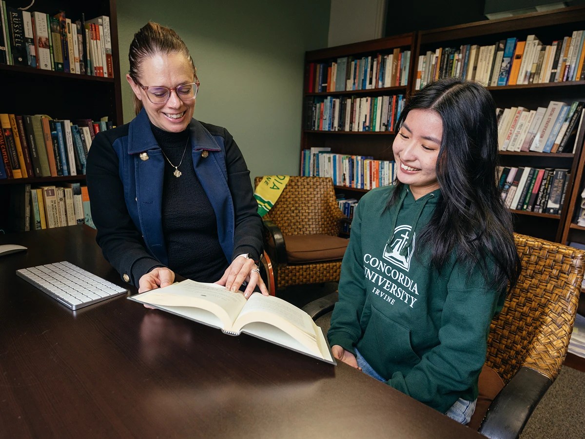A woman showing a book to a woman