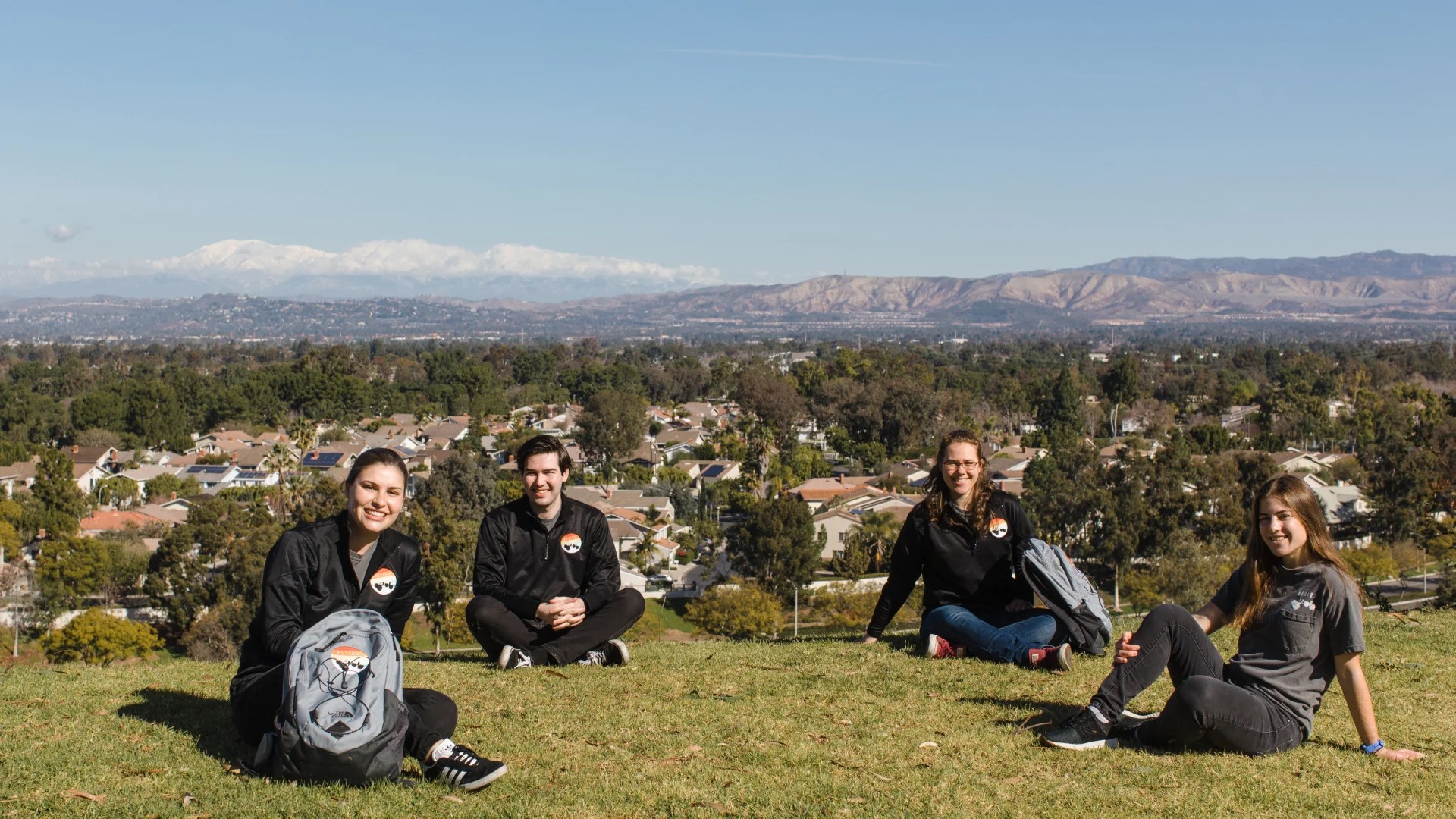 A group of people sitting on a hill with a city in the background