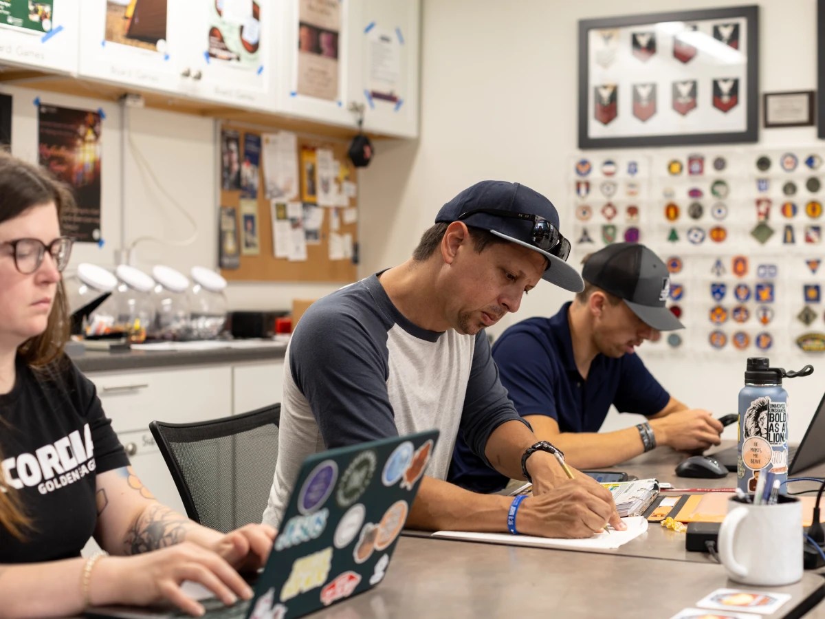 A group of men sitting at a table writing on a paper