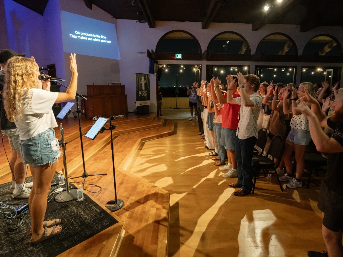 A woman singing into a microphone with a group of people in front of them