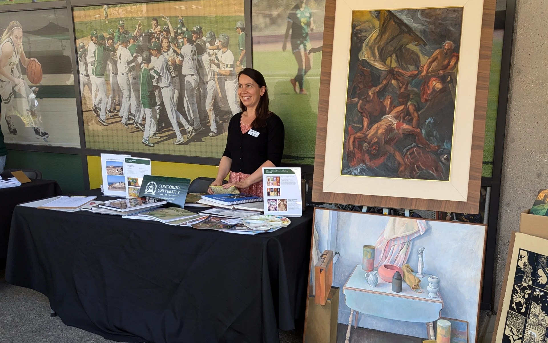 A woman standing behind a table with art and paintings