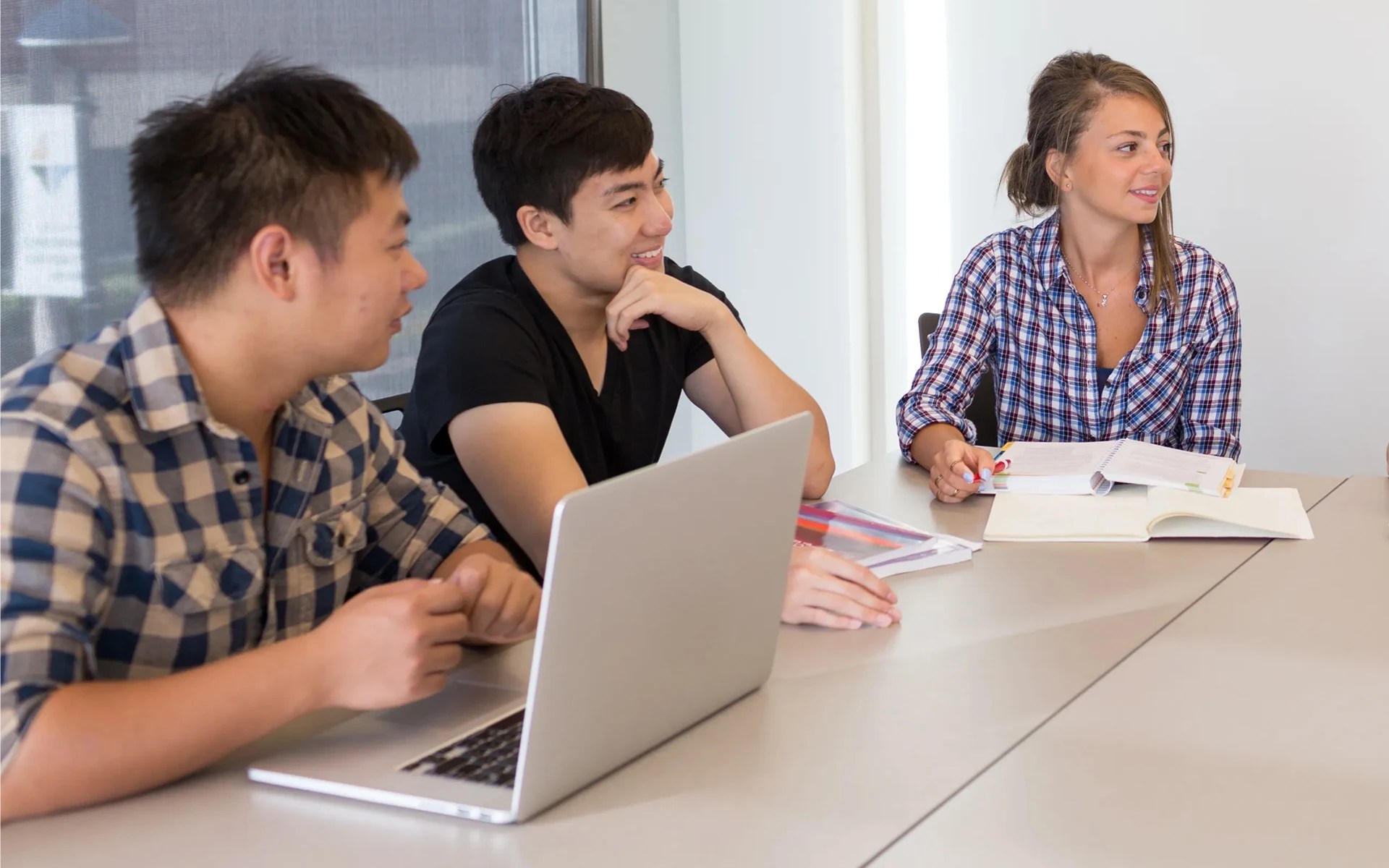 A group of people sitting at a table with a laptop