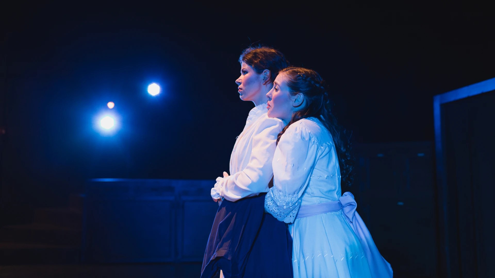 Two women in white dresses on a stage