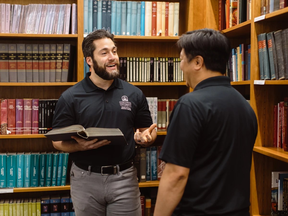 A man talking to another man in a library