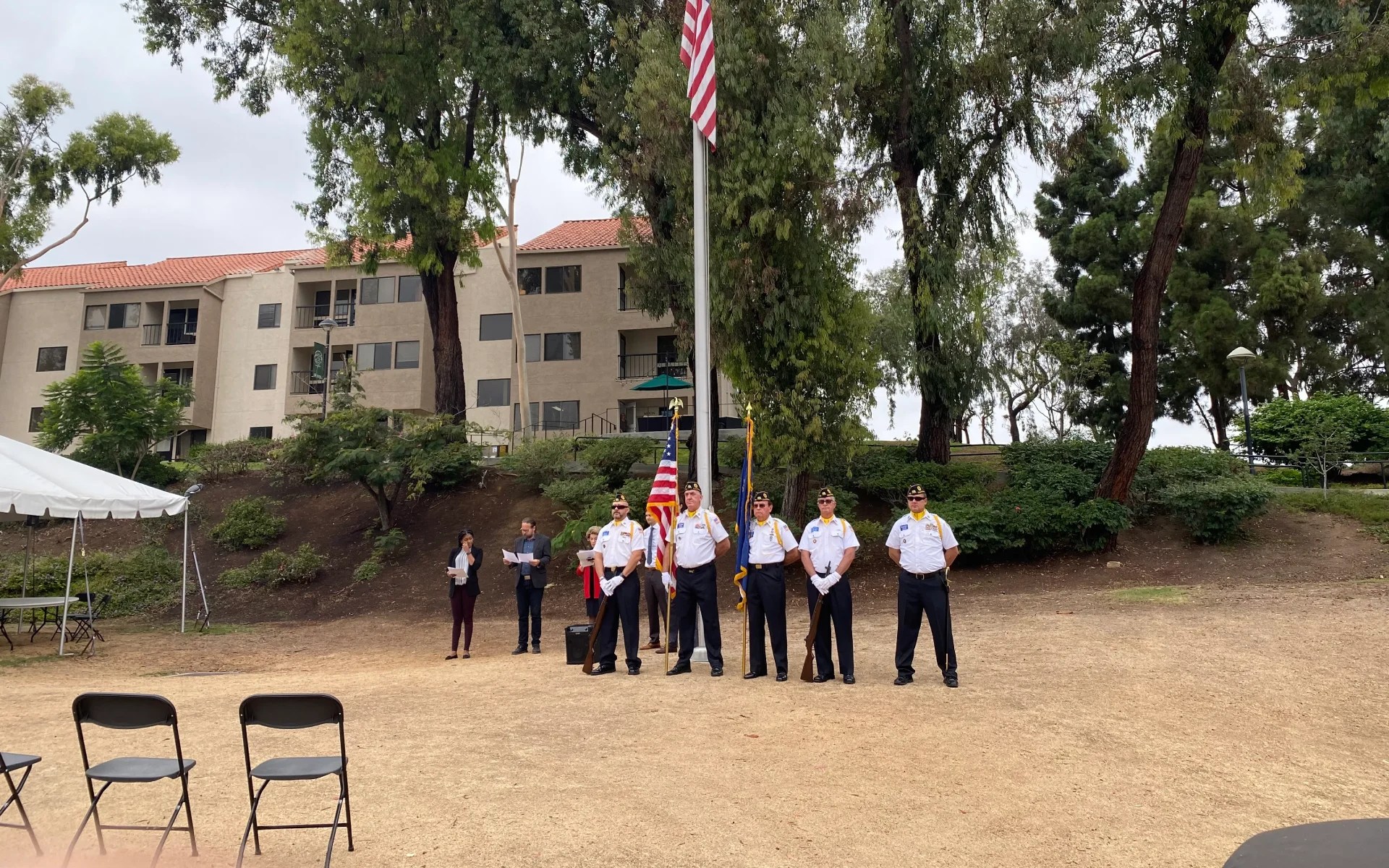 A group of people standing in front of a flag pole