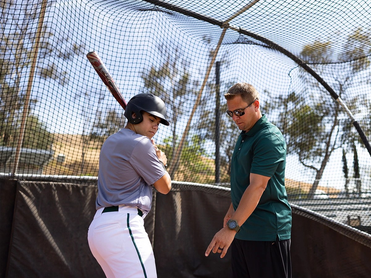 A man holding a baseball bat and standing next to a man
